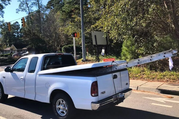 How far can a ladder stick out the back of a truck